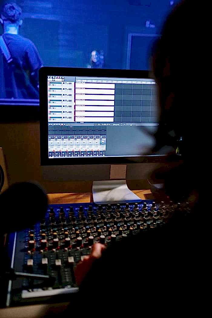 services-01 A recording artist working on audio mixing at a sound studio workstation.